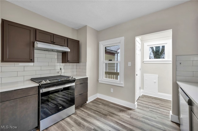 kitchen with under cabinet range hood, stainless steel electric range oven, light countertops, and dishwasher