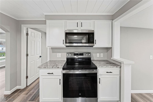 kitchen with stainless steel appliances, light wood-style floors, white cabinets, and light stone counters