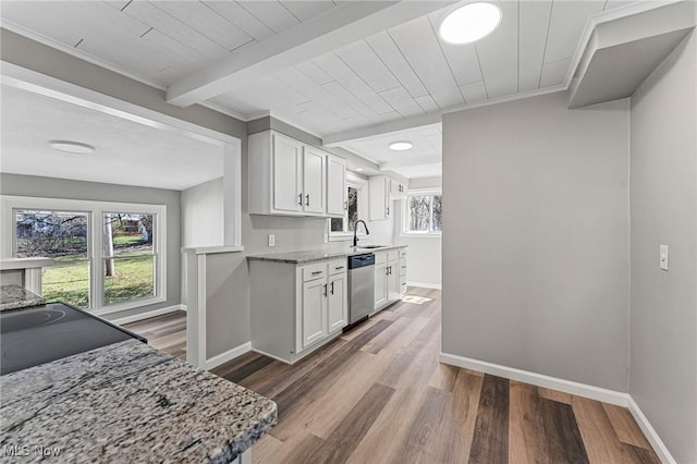 kitchen featuring baseboards, white cabinets, beamed ceiling, stainless steel dishwasher, and wood finished floors