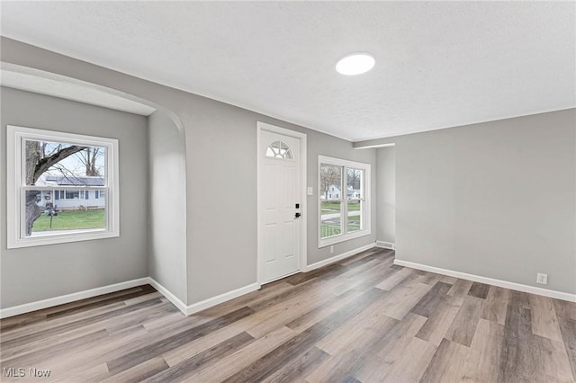 entrance foyer with a textured ceiling, wood finished floors, baseboards, and arched walkways