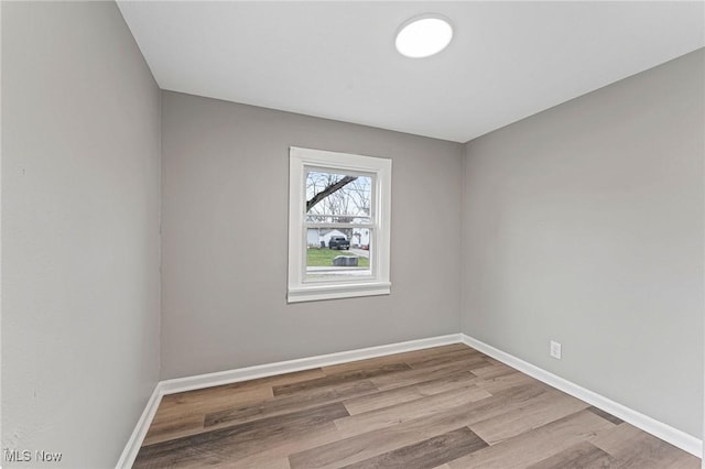 spare room with baseboards and wood finished floors