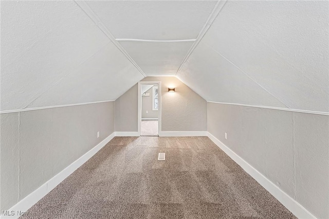 bonus room featuring a textured wall, carpet flooring, baseboards, and lofted ceiling