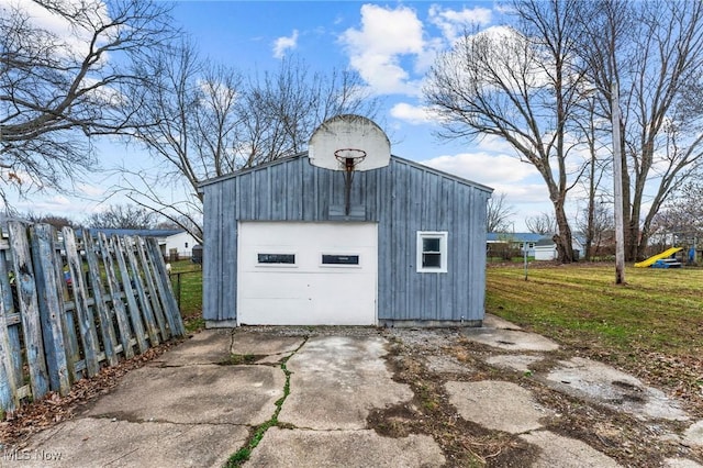 detached garage featuring driveway and fence