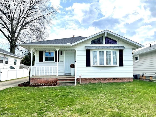 view of front of property with central air condition unit, a front lawn, covered porch, fence, and roof with shingles