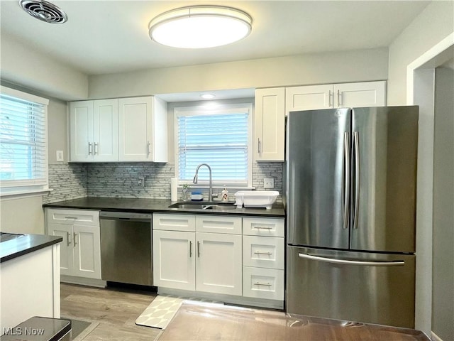 kitchen with dark countertops, visible vents, a sink, appliances with stainless steel finishes, and white cabinetry