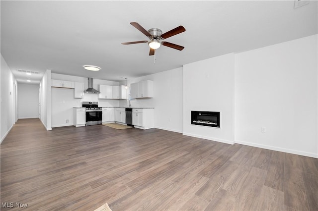 1996 E Oldgate Rd, Sandusky, OH 44870 - unfurnished living room featuring dark wood-type flooring, a ceiling fan, a glass covered fireplace, a sink, and baseboards