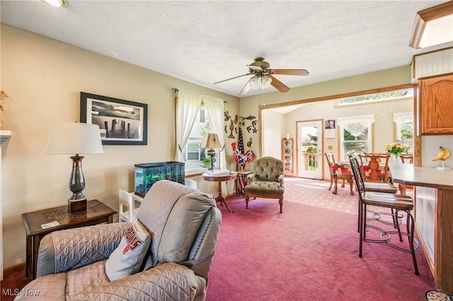 carpeted living area with a textured ceiling and a ceiling fan
