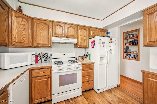 kitchen featuring white appliances, light countertops, under cabinet range hood, brown cabinets, and light wood finished floors