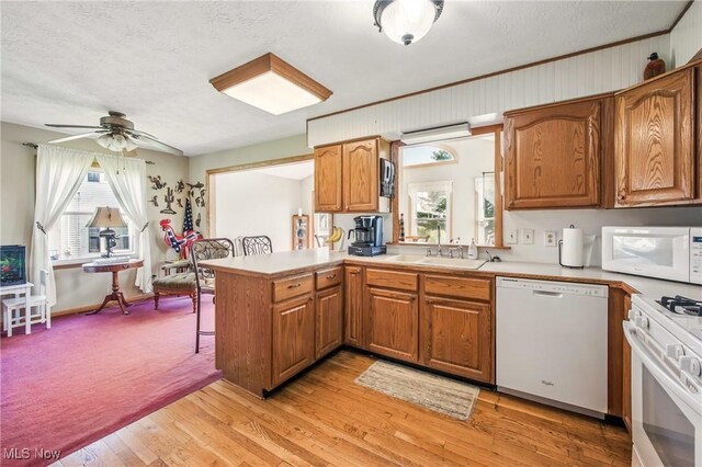 kitchen with white appliances, light countertops, a sink, and a peninsula
