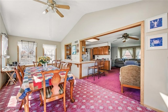 carpeted dining room with lofted ceiling, visible vents, and ceiling fan