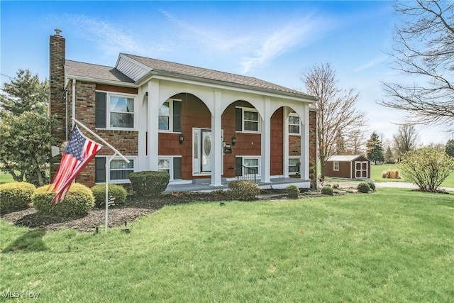 split foyer home featuring a chimney, a shed, a front yard, an outbuilding, and covered porch