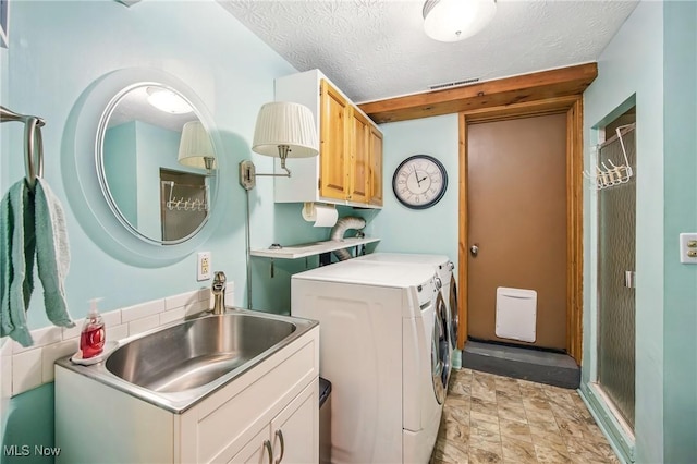 laundry room with visible vents, a sink, a textured ceiling, cabinet space, and washer and clothes dryer