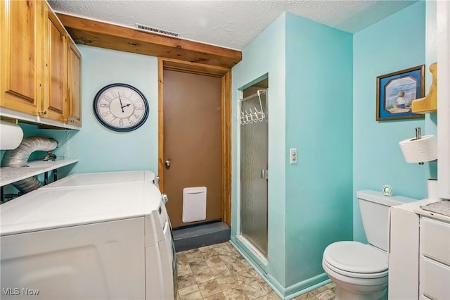 bathroom with baseboards, a stall shower, toilet, visible vents, and washing machine and clothes dryer