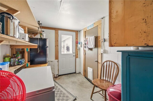 kitchen with freestanding refrigerator and unfinished concrete flooring