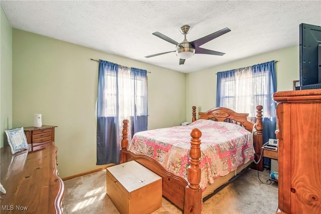 carpeted bedroom with a textured ceiling, baseboards, and a ceiling fan