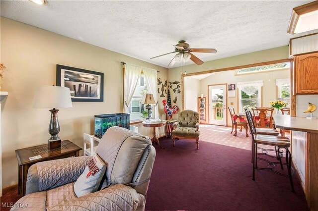 carpeted living area featuring ceiling fan and a textured ceiling