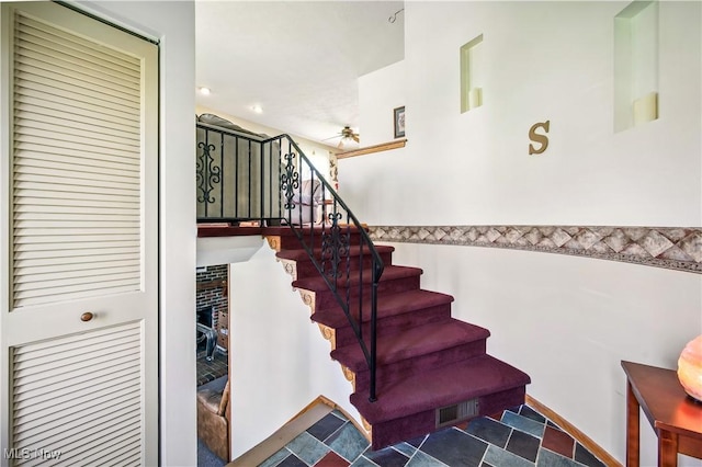 stairway with ceiling fan, a fireplace, and visible vents