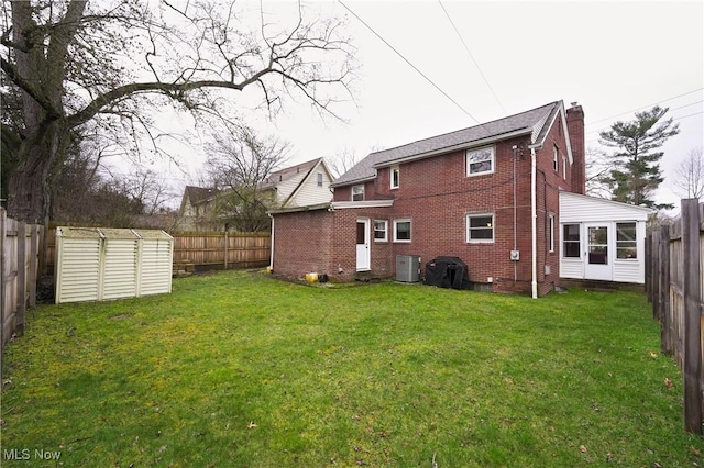 back of property featuring a yard, brick siding, a fenced backyard, and a chimney