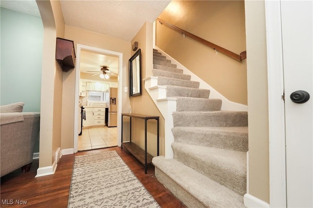 entrance foyer with baseboards, ceiling fan, dark wood finished floors, a textured ceiling, and stairs