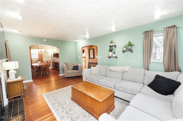living area with arched walkways, baseboards, and wood finished floors