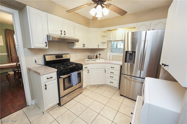 kitchen with light tile patterned floors, backsplash, under cabinet range hood, appliances with stainless steel finishes, and a sink
