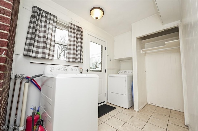 washroom with washer and clothes dryer, light tile patterned flooring, and laundry area