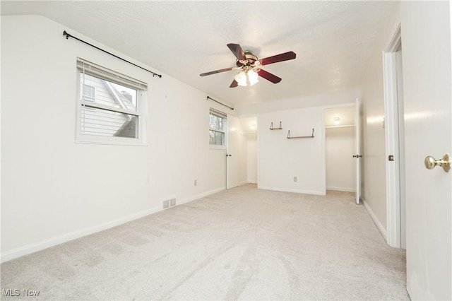 unfurnished room with baseboards, vaulted ceiling, a ceiling fan, visible vents, and light colored carpet