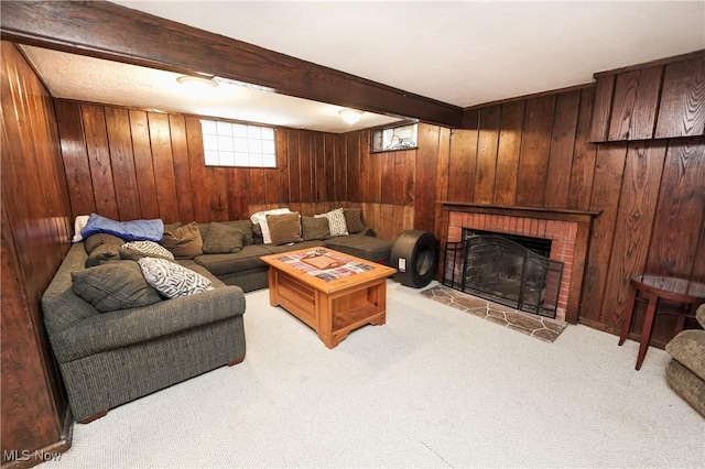 living area with wood walls, a brick fireplace, beamed ceiling, and carpet floors