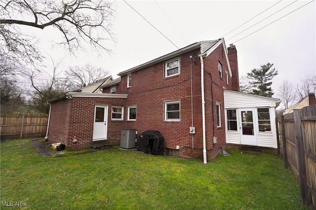 back of property with a chimney, a yard, a fenced backyard, and brick siding