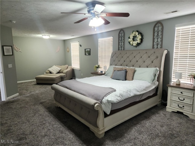 carpeted bedroom with visible vents, baseboards, multiple windows, and a textured ceiling