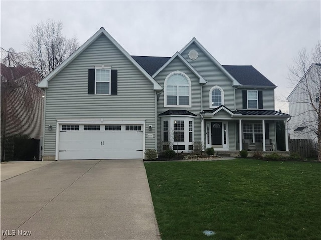 traditional home featuring concrete driveway, a garage, a front yard, a standing seam roof, and metal roof
