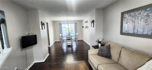 living area with a textured ceiling, baseboards, and wood finished floors