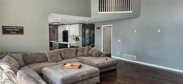 living room with a towering ceiling, baseboards, recessed lighting, visible vents, and wood finished floors