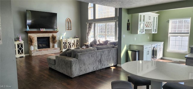 living room featuring a glass covered fireplace, dark wood-type flooring, baseboards, and wine cooler