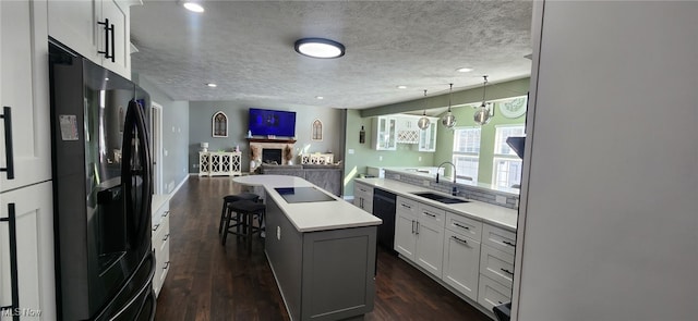 kitchen with open floor plan, light countertops, black appliances, dark wood finished floors, and a sink
