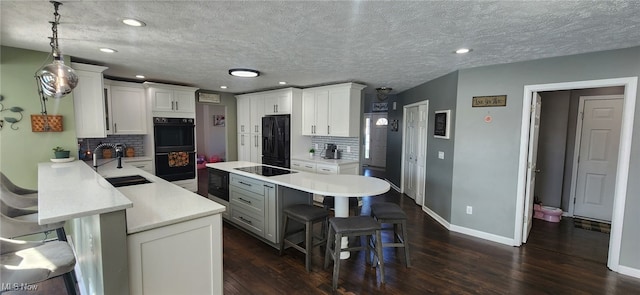 kitchen with light countertops, a breakfast bar area, a sink, and black appliances