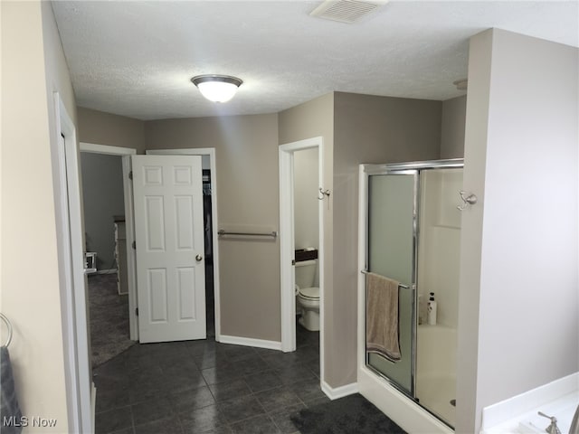 bathroom featuring visible vents, baseboards, toilet, a textured ceiling, and a shower stall