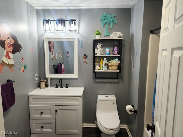 bathroom with toilet, vanity, and baseboards
