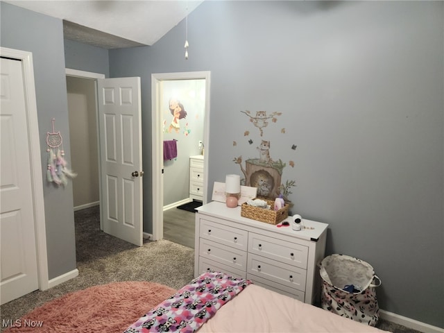 carpeted bedroom featuring ensuite bathroom, baseboards, and lofted ceiling