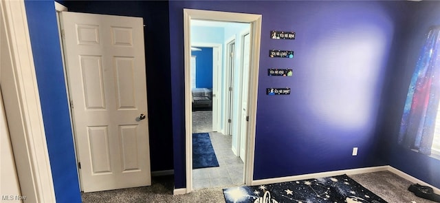hallway featuring baseboards and carpet