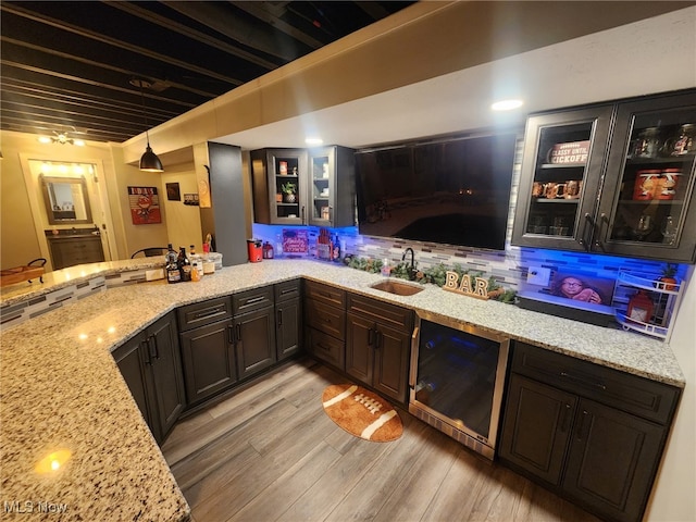 bar with decorative light fixtures, light wood-style floors, decorative backsplash, and a sink