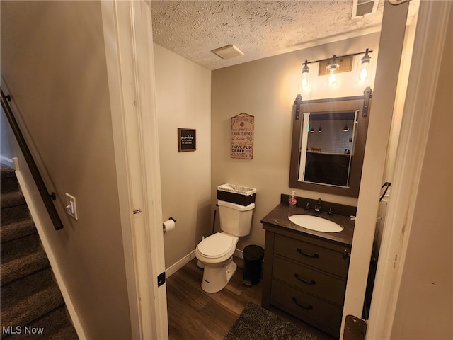 bathroom with visible vents, toilet, a textured ceiling, vanity, and wood finished floors