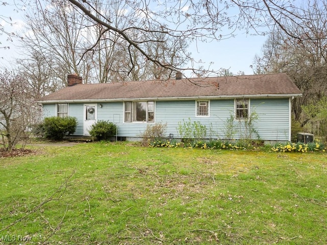 back of house with cooling unit, a lawn, and a chimney