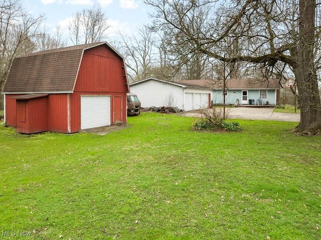 view of yard featuring a barn, driveway, an outbuilding, and a detached garage