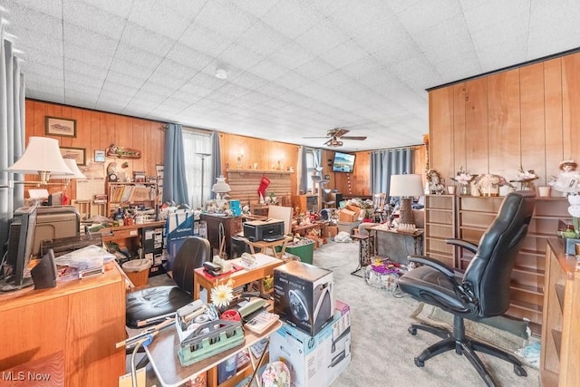 carpeted office featuring wood walls and a ceiling fan