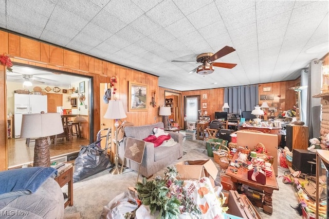 carpeted living room with wood walls and a ceiling fan