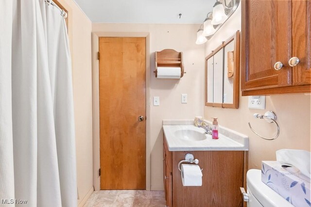 bathroom with a shower with shower curtain, vanity, marble finish floor, and toilet