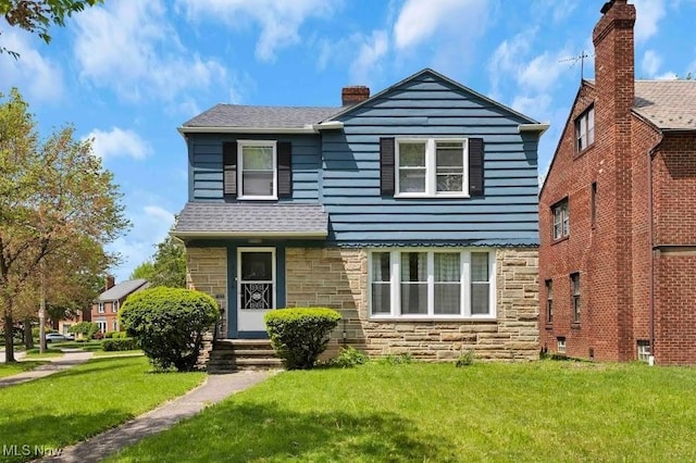 2374 Traymore Rd, University Heights, OH 44118 - view of front of house featuring stone siding, a front lawn, a chimney, and a shingled roof