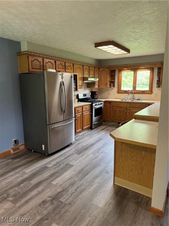 4966 Everett Hull Rd, Cortland, OH 44410 - kitchen featuring stainless steel appliances, a textured ceiling, under cabinet range hood, wood finished floors, and brown cabinets