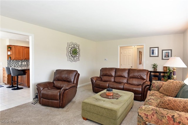 living area with light tile patterned floors, light colored carpet, and baseboards